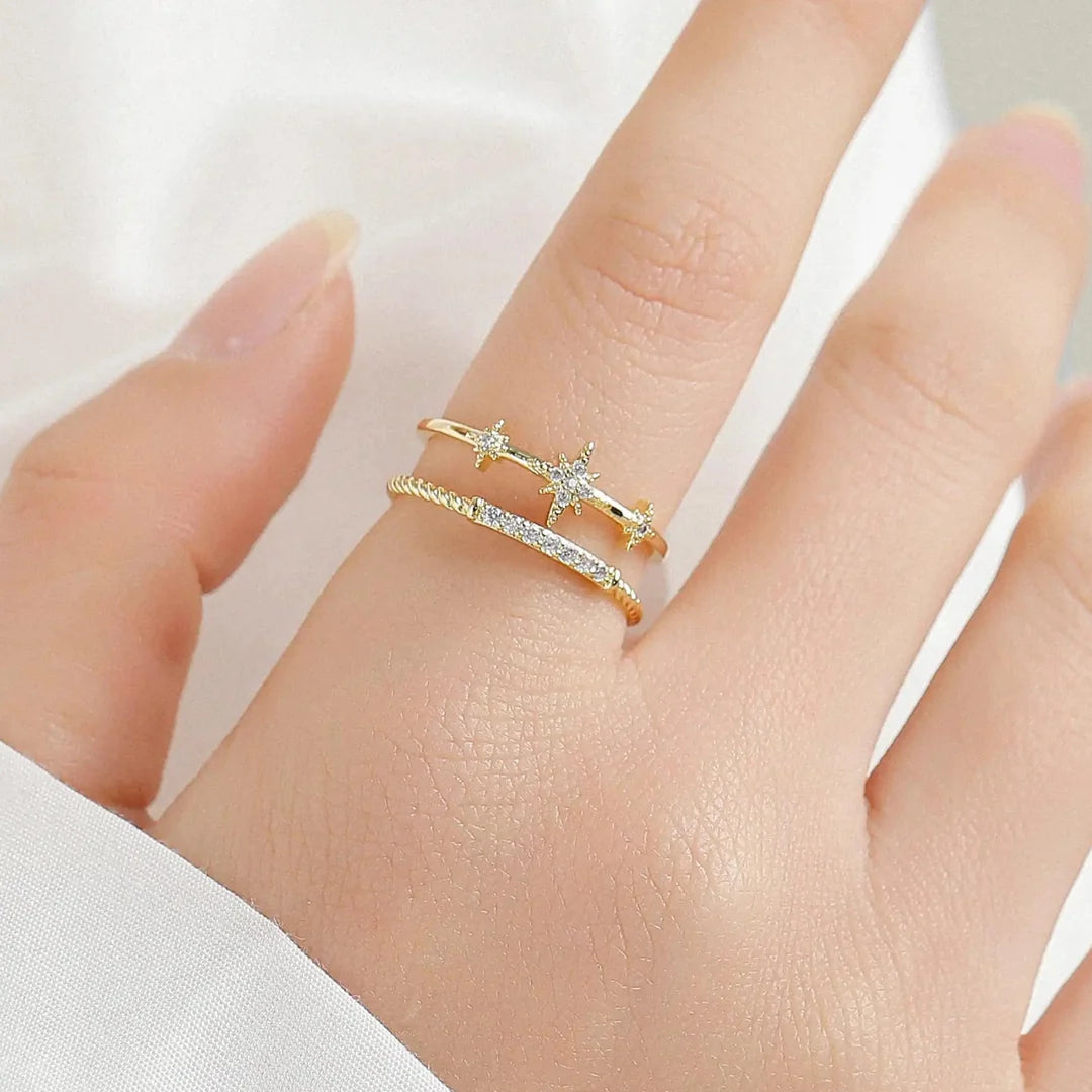 On-body styling illustration: real photograph of the Celestial Triple Star Ring worn on a finger.