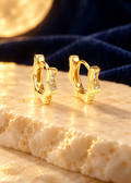 Styled editorial image of Starburst Huggie Hoops; AI-created setting. Original product photo also included.
